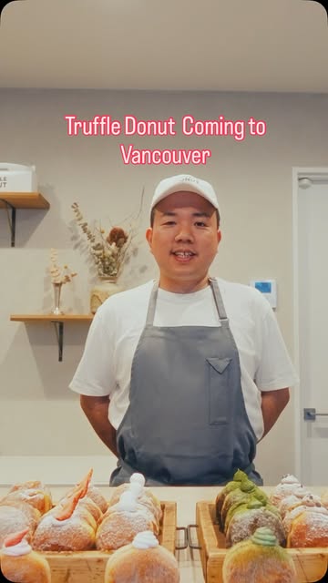 A Truffle Donut baker standing behind a display of fresh filled donuts